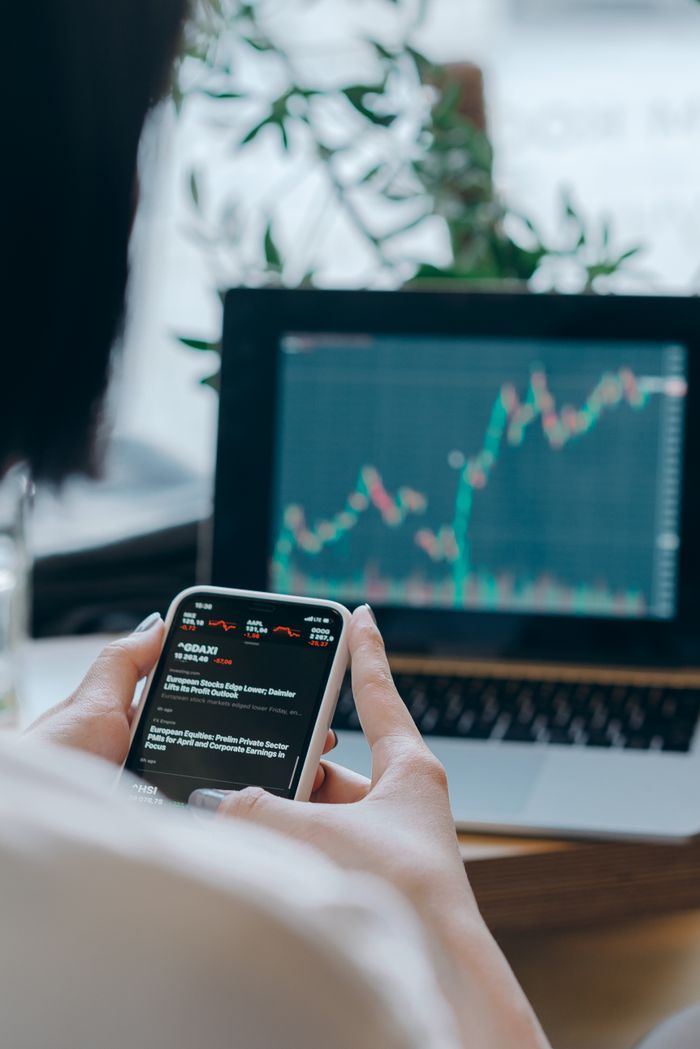 heros-img Person using smartphone for stock market analysis at home office.